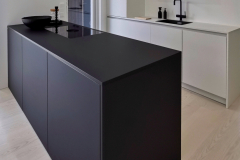 Tässä keittiössä yhdistetty rohkeasti täysin musta saareke muuten valkoisiin kalusteisiin.