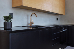 Tamminen seinäkaapisto tuo lämpöä tähän mustaan keittiöön