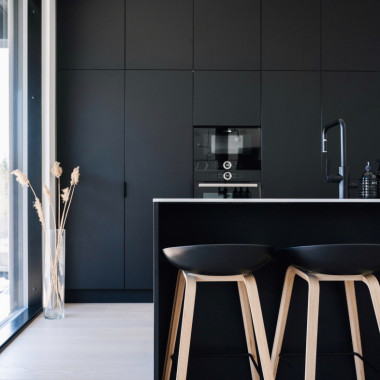 Musta täyskorkea keittiö antaa ryhtiä avaraan tilaan