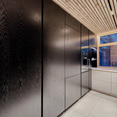 Musta tamminen kalusteseinä jatkuu lattiasta kattoon, ikkunasta seinään saakka.