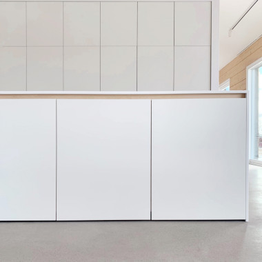 Minimalistinen valkoinen keittiö hirsitalossa. Massiivikoivuinen profiilijärjestelmä lämmittää kalusteet.