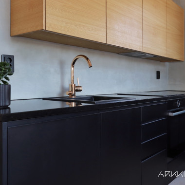 Tamminen seinäkaapisto tuo lämpöä tähän mustaan keittiöön